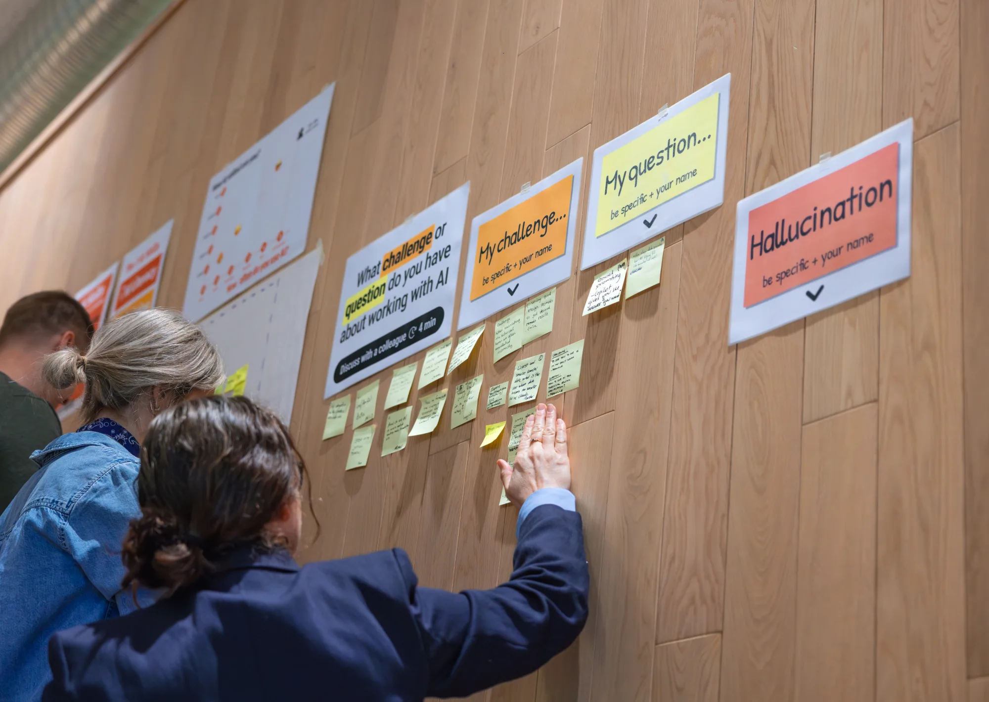 Team bekijkt samen een muur met post-its tijdens een werksessie bij Stokke