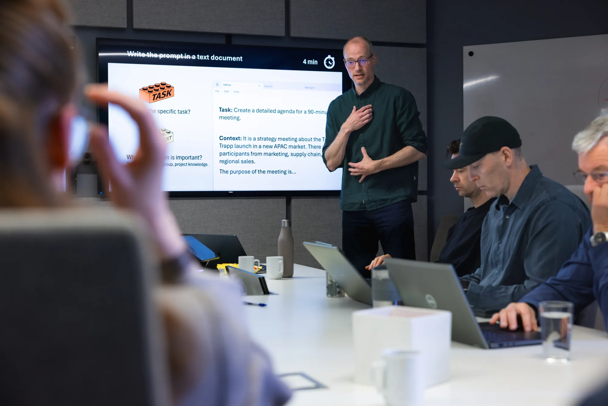Werksessie bij Stokke in Oslo: trainer legt een prompt-aanpak uit aan een team met laptops